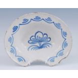 A French blue and white faience barber's shaving bowl, 19th century, the well decorated with a