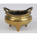 A Chinese gilt bronze tripod censer, having simple loop handles, the interior cast with a coiled