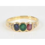 A yellow metal multi-stone dress ring, comprising an oval ruby, emerald and sapphire all in bezel