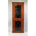 A late Victorian freestanding satinwood corner cabinet, in two sections, having a dentil moulded