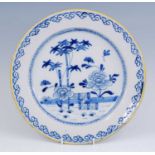 A Dutch blue and white charger, 18th century, decorated with flowers before a fence within a