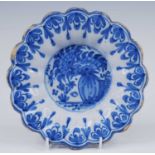 A Delft blue and white dish, late 17th century, of lobed form, the well decorated with a vase of