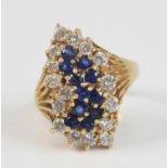 A modern yellow metal, sapphire and diamond abstract cluster ring, the eleven claw-set blue