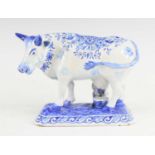 A Delft blue and white model of a cow, probably 19th century, shown in standing pose, decorated with