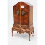 A miniature walnut table top cabinet in the style of a Queen Anne cabinet on stand, with arched