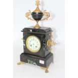 A late 19th century black slate and marble cased mantel clock, surmounted by an urn having a