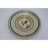 A continental terracotta and slip-glazed dish, the centre decorated with a bird within geometric and