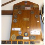 An oak noticeboard containing assorted motoring interest enamel and brass badges, 96 x 54cm;