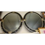 A pair of reproduction silvered and black composition framed and bevelled oval wall mirrors, 110 x