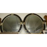 A pair of silvered and black composition framed and bevelled oval wall mirrors, 110 x 95cm