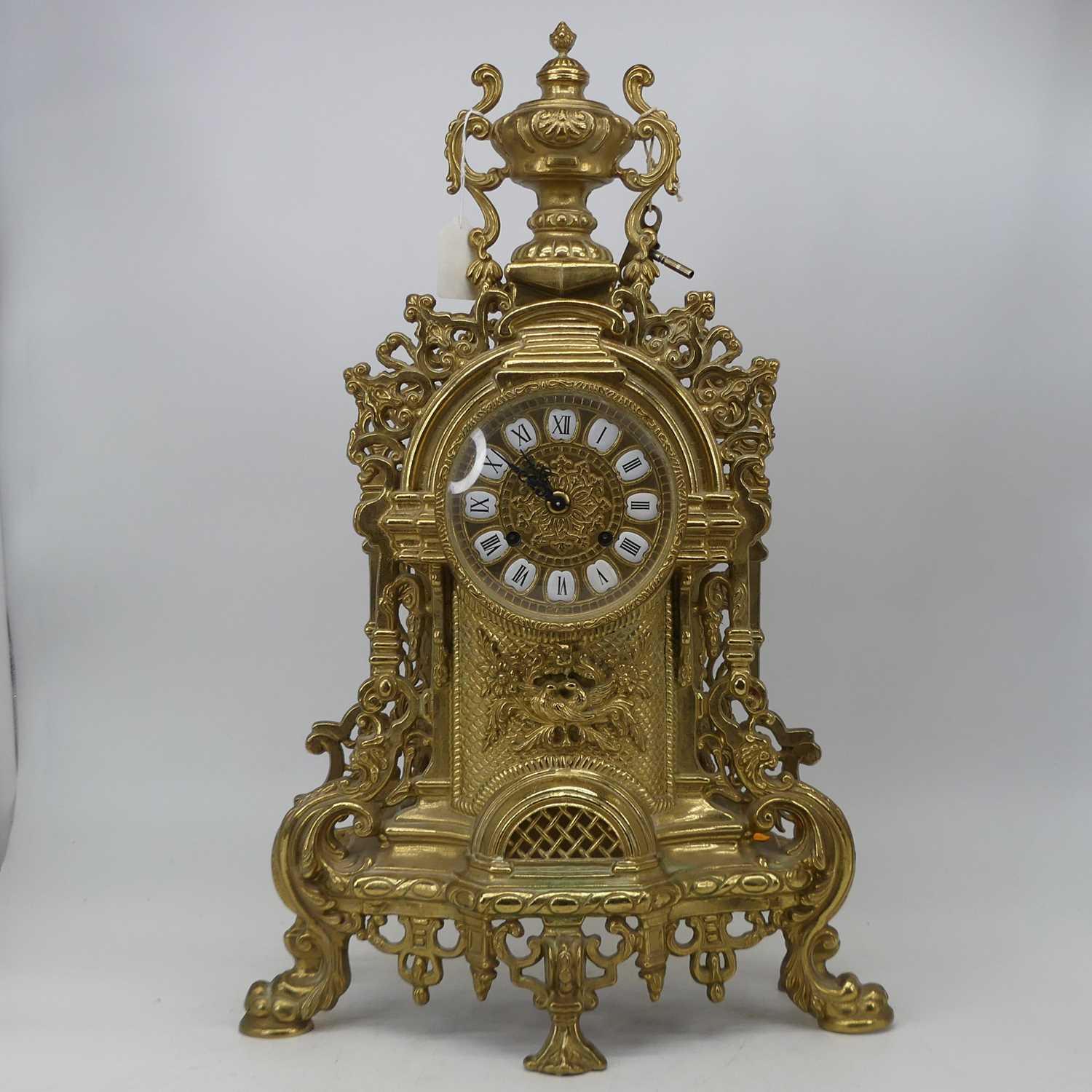 A large 18th century style brass cased mantel clock, the circular dial with raised enamelled plaques