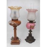 A Victorian oil lamp, having a pink tinted shade above a pink glass hand-painted font upon cast iron