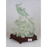 A Chinese carved and polished hardstone model of a phoenix perched upon a flower, standing upon