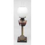 A Victorian oil lamp having an opalescent globular shade above a glass font on a fluted column and