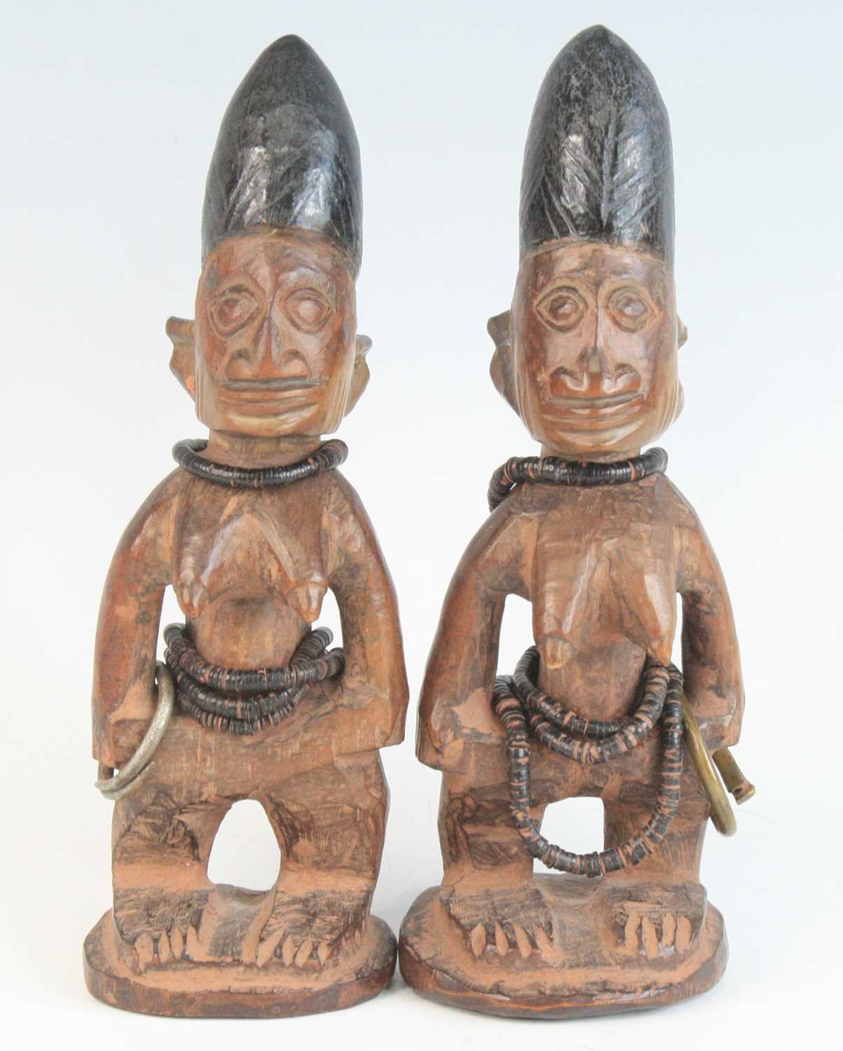 A pair of Ibeji figures, each carved as a female in standing pose with scarified cheeks and