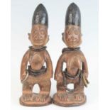 A pair of Ibeji figures, each carved as a female in standing pose with scarified cheeks and