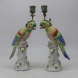 A pair of modern Continental porcelain table candlesticks, each in the form of a parrot perched on a