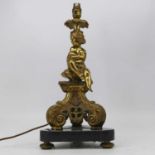 An early 20th century gilt brass table candle stick, having a single sconce surmounted by a seated