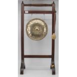An early 20th century dinner gong, the circular brass gong suspended from a mahogany frame, with