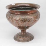 An Arts & Crafts copper jardiniere of squat circular form repoussee decorated with leaves and