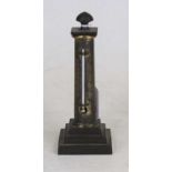 A 19th century brass table thermometer in the form of a Doric column, upon a square stepped