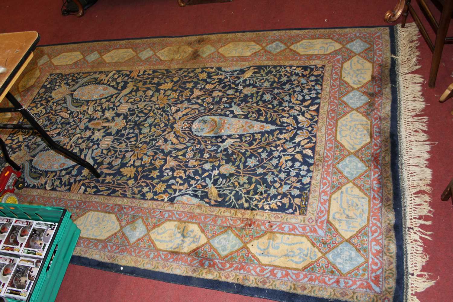 A Persian woollen blue ground rug, the heavily decorated central ground within trailing tramline