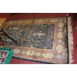 A Persian woollen blue ground rug, the heavily decorated central ground within trailing tramline