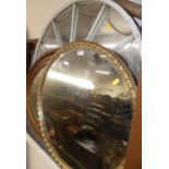 A gilt composition framed and bevelled oval wall mirror, dia.64cm; together with a gilded and