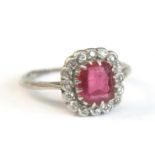 A white metal, ruby and diamond cushion shaped cluster ring, featuring a centre cushion cut ruby