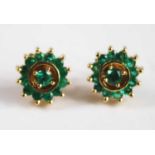 A pair of yellow metal emerald circular cluster earrings each comprising a centre round single stone