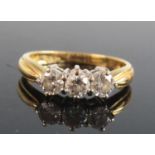 An 18ct yellow and white gold diamond trilogy ring, featuring three round brilliant cut diamonds