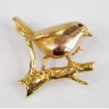 A 9ct yellow gold brooch depicting a robin on a branch with rose gold detail for the breast and a