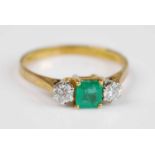 An 18ct yellow and white gold emerald and diamond three stone ring featuring a centre octagonal