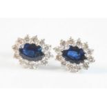 A pair of 18ct white gold, sapphire and diamond oval cluster earrings, each featuring a centre