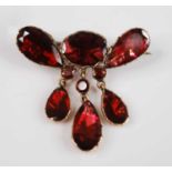 A yellow metal bar brooch with one oval, five pear cut and three round garnets in foil closed back