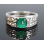 A white metal and emerald and diamond dress ring comprising a centre octaganal cut emerald in a claw