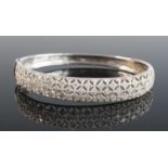 A 9ct white gold diamond hinged oval hollow bangle, featuring a lattice-work section at the front