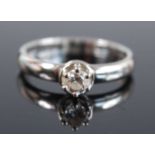 A white metal diamond solitaire ring, featuring a round brilliant cut diamond in a claw and bezel