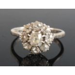 A white metal diamond circular cluster ring, comprising a centre old mine cut diamond within a