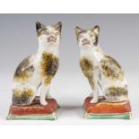 A pair of Victorian Staffordshire pearlware models of cats, each shown in seated pose upon a