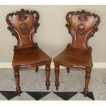 A pair of mid-Victorian mahogany floral scroll carved and panelled seat hall chairs, the