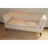 A Victorian mahogany framed three-seater sofa by Howard & Sons, pale fabric upholstered, raised on