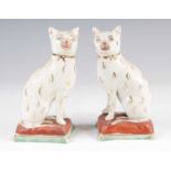 A pair of Victorian Staffordshire pearlware models of cats, each shown in seated pose upon a