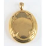 A yellow metal oval locket, having a raised scalloped pattern with a photograph of a Victorian