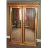 A Victorian maple twin mirror door wardrobe, having a proud railed cornice, enclosing hanging