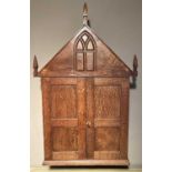 An early 20th century joined oak double door wall cupboard in the ecclesiastical taste, with a