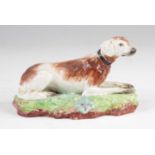 A Neale & Co pearlware model of a dog, early 19th century, shown in recumbent pose, impressed