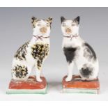 A matched pair of Victorian Staffordshire models of cats, each shown in seated pose upon a