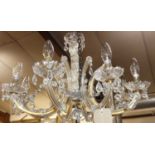 An early 20th century cut crystal glass eight light chandelier, having C-scroll branch arms,