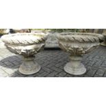 A pair of reconstituted stone circular pedestal garden planters, each heavily floral decorated in